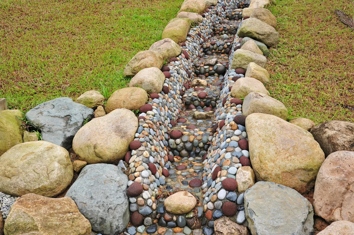 Dry creek bed swale lined with river rock carrying yard runoff