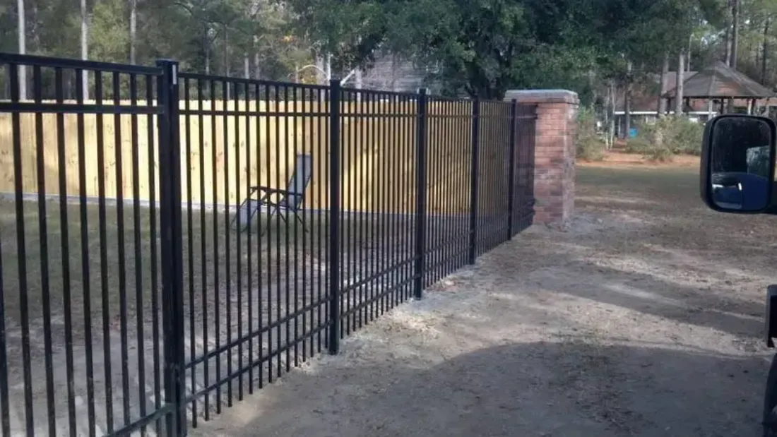 Black aluminum fence with brick columns along a property line on the Northshore