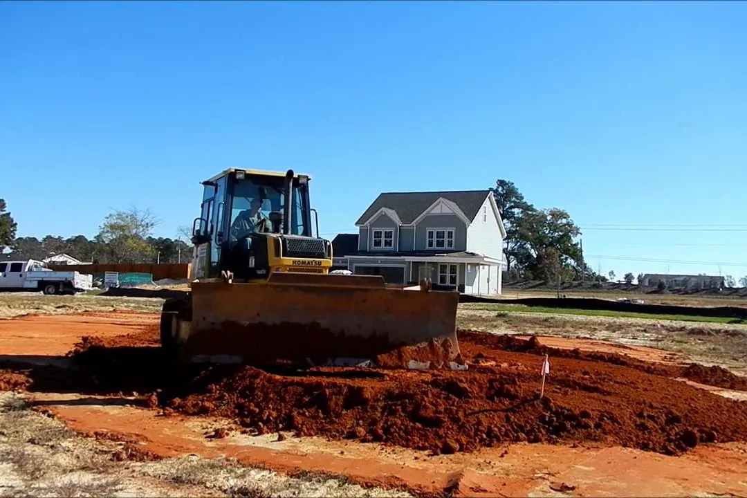 Dozer pushing red clay fill to build up a house pad on a new home lot
